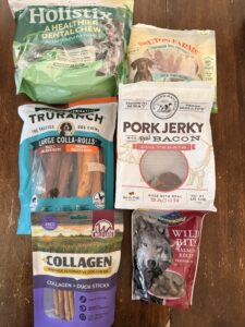 Assortment of rawhide alternative chews and dog treats for Akita puppy Kodi including TruRanch Holistix Wild Eats and Blue Wilderness